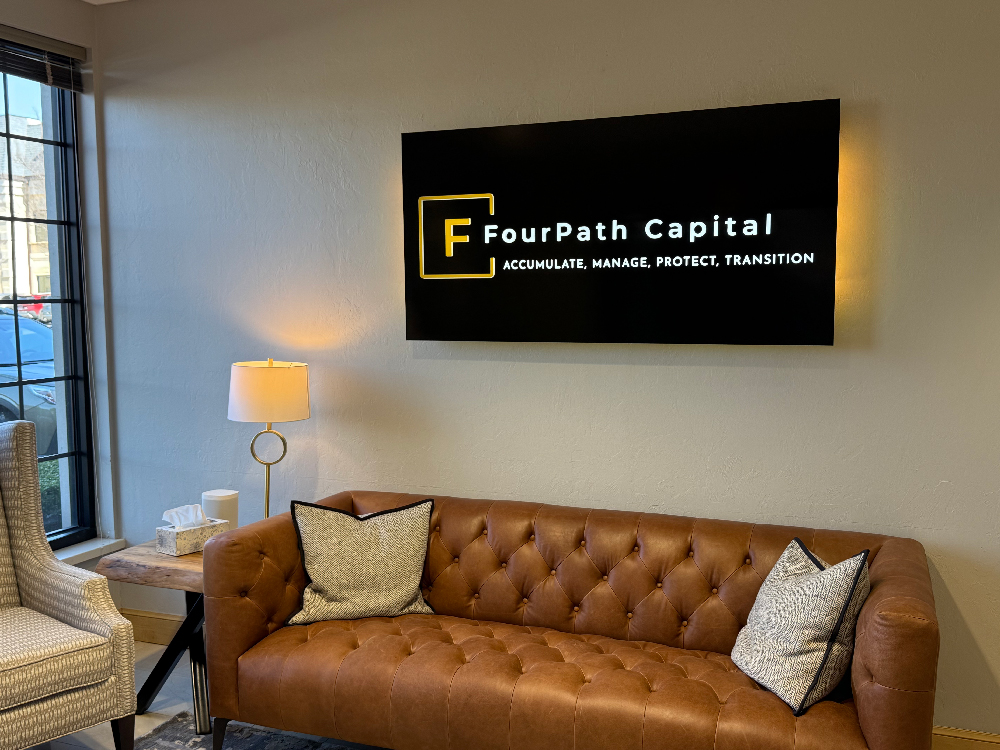A photo of a rectangle wall sign that is black with a gold halo around the outside,  and a lit logo of the company name.