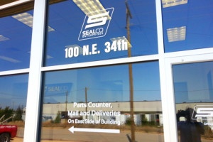 Photo of exterior business door hours and logo decals.
