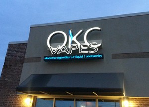 Illuminated channel letter logo sign with illumination attached to side of building.
